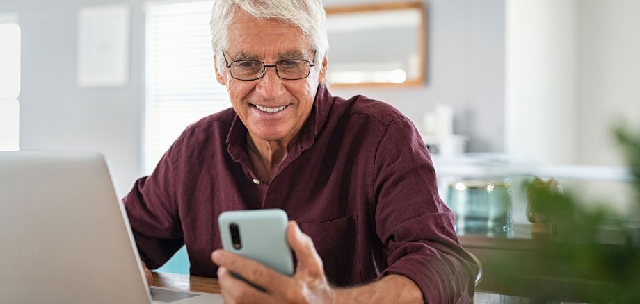 Senior man working on laptop and using smartphone