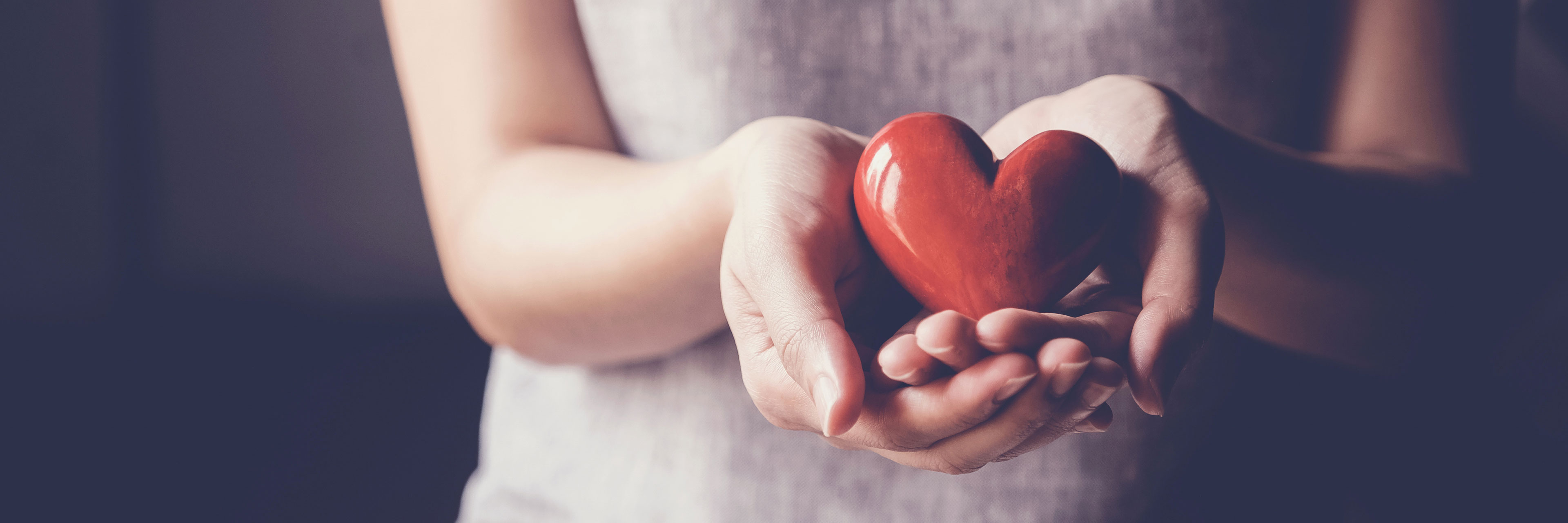 Eine Frau, die ein rotes Herz in ihren Händen hält.