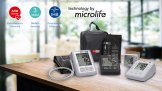 BMG Web Technologien Aponorm Blutdruckmessgeräte: vier verschiedene Modelle mit Tasche liegen auf einem holzernen Tisch. Der Hintergrund ist verschwommen.