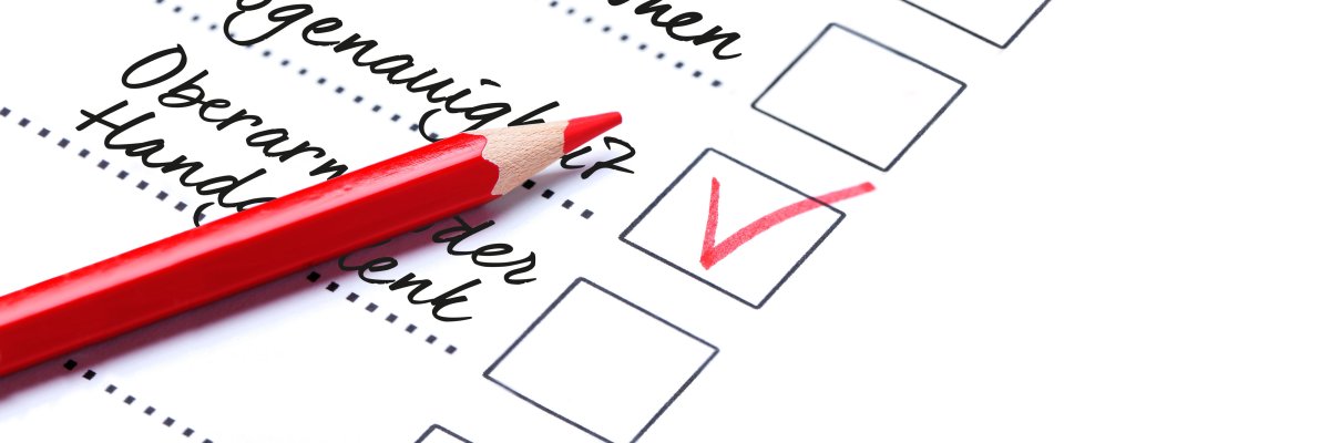 ine To-do-Liste, auf der ein roter Stift liegt, ein Häckchen ist mit einem roten Haken.