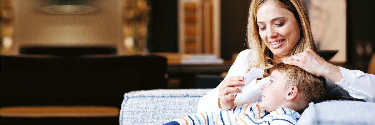 Eine Mutter, die ihrem Kind an der Stirn mit einem Stirnthermometer die Temperatur misst.
