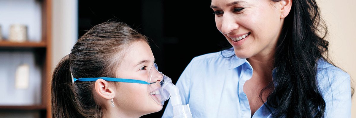 Mutter und Tochter- die Tochter inhaliert mit einer Maske in Nahaufnahme